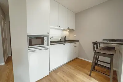 a kitchen with white cabinets and a microwave and a stool at Crystal Palace Garden Stylish Apartment by Vacationy in Porto