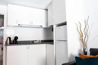 a white kitchen with white cabinets and a blue chair at Almada Downtown 103 in Porto