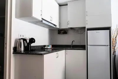 a white kitchen with white cabinets and a refrigerator at Almada Downtown 103 in Porto