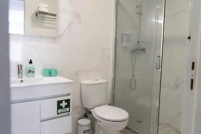 a white bathroom with a toilet and a shower at Almada Downtown 103 in Porto