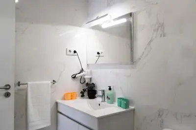 a white bathroom with a sink and a mirror at Almada Downtown 103 in Porto