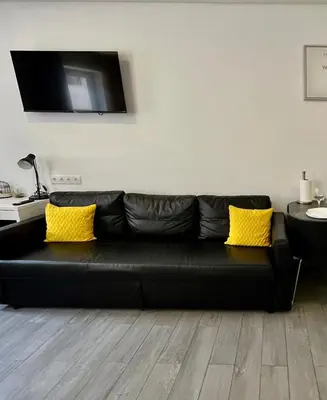 a black leather couch in a living room with yellow pillows at Almada Downtown 201 in Porto