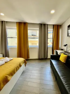 a bedroom with a bed and a couch and windows at Almada Downtown 201 in Porto