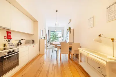 a kitchen with white cabinets and a table with chairs at Republica I by Innkeeper in Porto