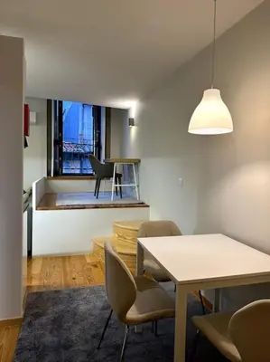 a dining room with a table and chairs and a window at Almada One in Porto