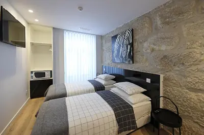 a bedroom with two beds and a stone wall at FLH Porto Downtown GuestHouse in Porto