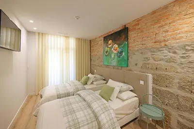a bedroom with two beds and a brick wall at FLH Porto Downtown GuestHouse in Porto