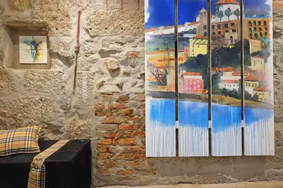 a wall with a painting on it next to a couch at FLH Porto Downtown GuestHouse in Porto