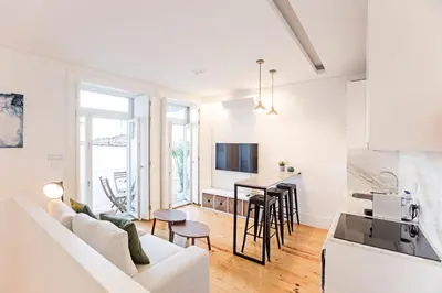 a white living room with a white couch and a kitchen at Wonderful Duplex W Private Patio & AC by LovelyStay in Porto