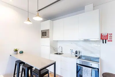 a white kitchen with a table and a sink at Wonderful Duplex W Private Patio & AC by LovelyStay in Porto