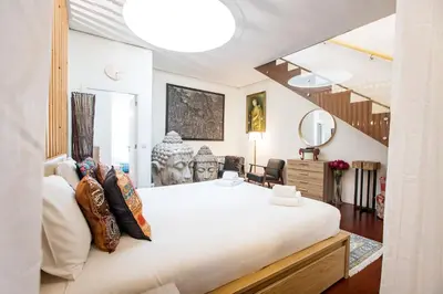 a bedroom with a large white bed and a staircase at GuestReady - Fantástico apt em Santa Catarina in Porto