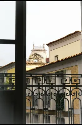 a building with a clock tower behind a fence at Rua das Flores Neighborhood in Porto