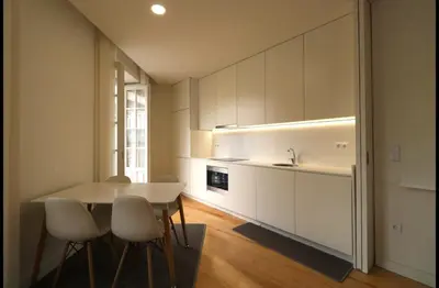 a kitchen with white cabinets and a table and chairs at Rua das Flores Neighborhood in Porto