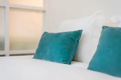 a white bed with two blue pillows on it at GuestReady - Rustic urban retreat in Porto