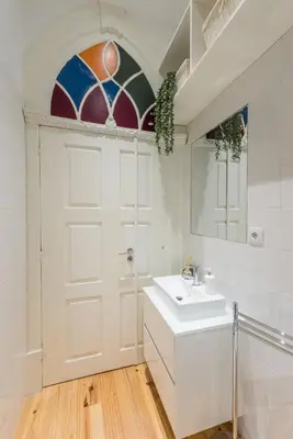 a white bathroom with a sink and a door at GuestReady - Rustic urban retreat in Porto