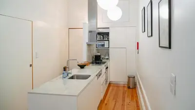 a white kitchen with white cabinets and a sink at Bolhão Studio, Porto in Porto