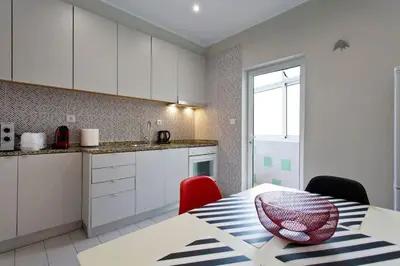 a kitchen with white cabinets and a table with red chairs at APOSENTUS - Serenity 1D in Porto
