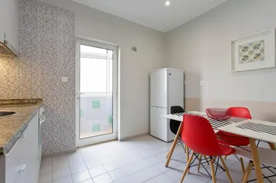 a kitchen with a table and red chairs and a refrigerator at APOSENTUS - Serenity 2D in Porto