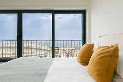 a white bed with yellow pillows in front of a window at Dragão Rooftop in Porto