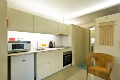 a kitchen with white cabinets and a chair in it at Oporto Cozy Flats in Porto