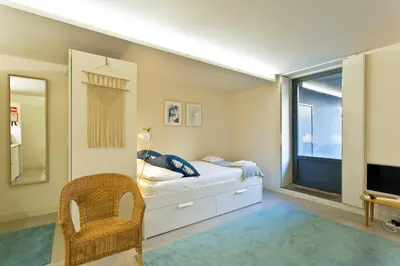 a bedroom with a bed and a window and a chair at Oporto Cozy Flats in Porto