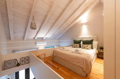 a bedroom with a large bed with a wooden ceiling at DOISPONTOZERO Oliveirinhas in Porto
