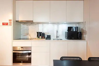 a kitchen with white cabinets and a microwave at DOISPONTOZERO Oliveirinhas in Porto