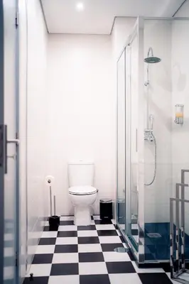 a bathroom with a toilet and a black and white checkered floor at Emotions Lapa Flat in Porto