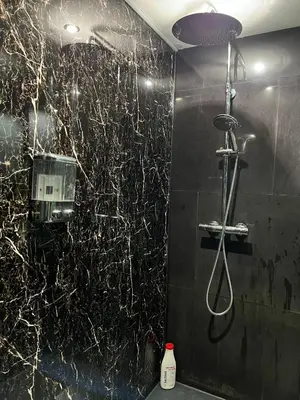 a bathroom with a shower with a black marble wall at Modern & Central 3 minutes from the River in Vila Nova de Gaia