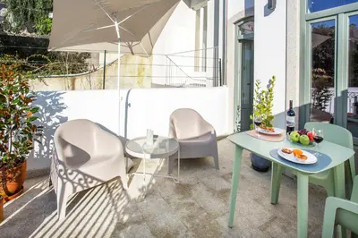 a patio with a table and chairs and an umbrella at WALAA Home@Almada Terrace by LovelyStay in Porto