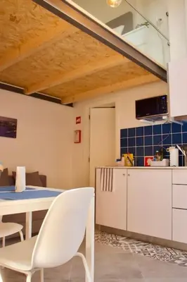 a kitchen with white chairs and a table and cabinets at Ilhas Douro - Fontaínhas by PA Hotels in Porto
