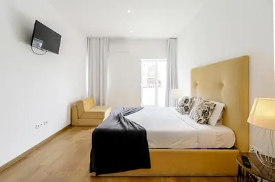 a bedroom with a large bed and a chair at Asgard Oporto Downtown Apartments in Porto