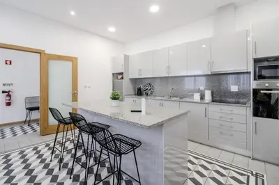 a kitchen with white cabinets and a counter with stools at Asgard Oporto Downtown Apartments in Porto