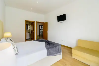 a bedroom with a white bed and a tv on the wall at Asgard Oporto Downtown Apartments in Porto