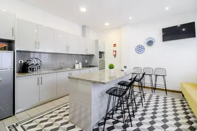 a kitchen with white cabinets and bar stools at Asgard Oporto Downtown Apartments in Porto