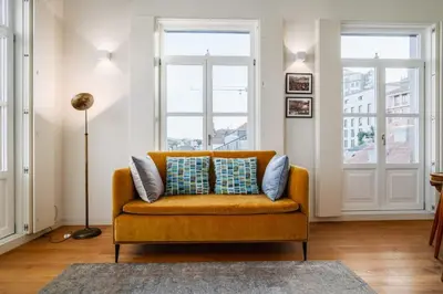 an orange couch in a living room with two windows at Victoria Luxury Apartment, Historic House Downtown in Porto