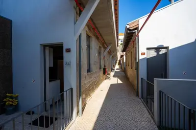 a narrow alley with white buildings and a gate at Ilha D’ouro House S. Vitor in Porto