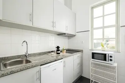 a white kitchen with a sink and a microwave at Porto InLapa Apartment II Terrace in Porto