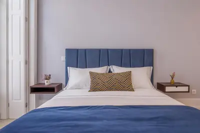 a bed with a blue headboard and two night stands at Porto Almada 180 Apartments in Porto
