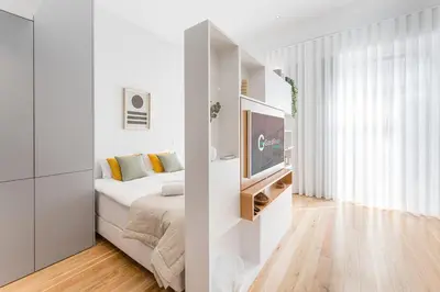 a white bedroom with a bed and a tv at GuestReady - Studio Five-0-Five in Porto