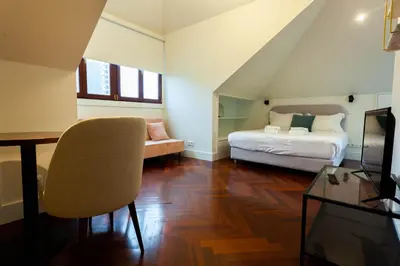 a bedroom with a bed and a couch and a tv at Trindade - Loft apartment in Porto