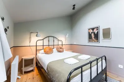 a bedroom with a bed with white sheets and orange pillows at GuestReady - Spacious and modern Apt W/ Skylight in Porto