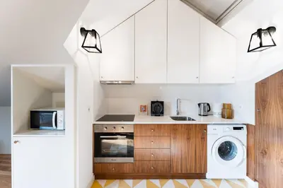 a kitchen with white cabinets and a washer and dryer at GuestReady - Spacious and modern Apt W/ Skylight in Porto