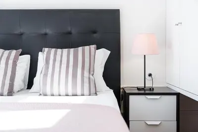 a bedroom with a bed with a black headboard and a lamp at GuestReady - Bright Apartment near Bolhão in Porto