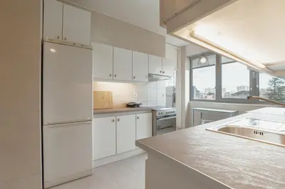 a kitchen with white cabinets and a stainless steel refrigerator at Grand Botanic Garden Apartment by Vacationy in Porto