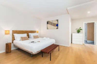 a white bedroom with a large bed and a bench at Dream On - Clérigos Lofts in Porto