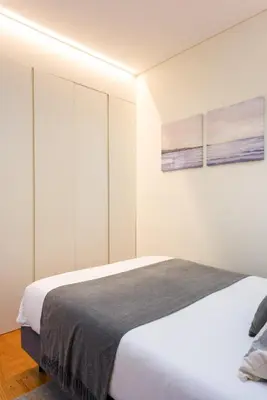 a bedroom with a large bed with white walls at Casa Barros - Trindade in Porto