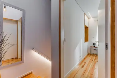 a hallway with white walls and a mirror at Design Antas Home in Porto