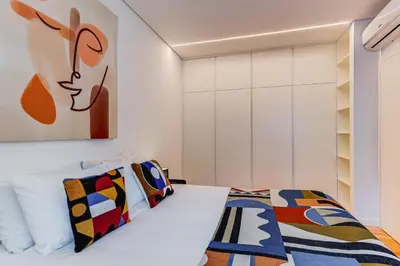 a bedroom with a white bed with colorful pillows at Design Antas Home in Porto