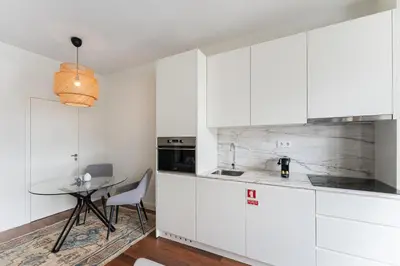 a kitchen with white cabinets and a table at GuestReady - Almada 516 in Porto